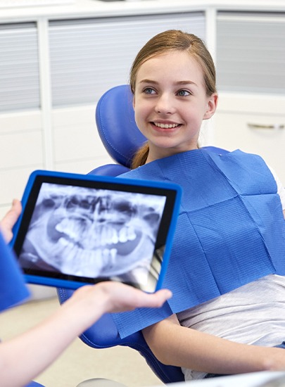Dentist talking to young patient about digital x-rays on tablet computer