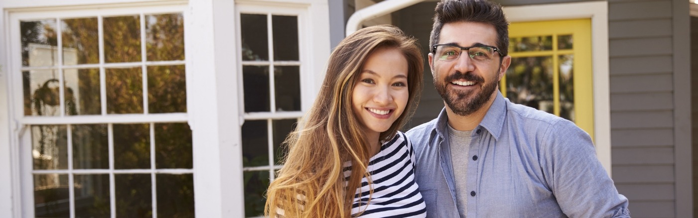 a couple smiling together in front of house