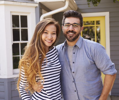 a couple smiling together in front of house