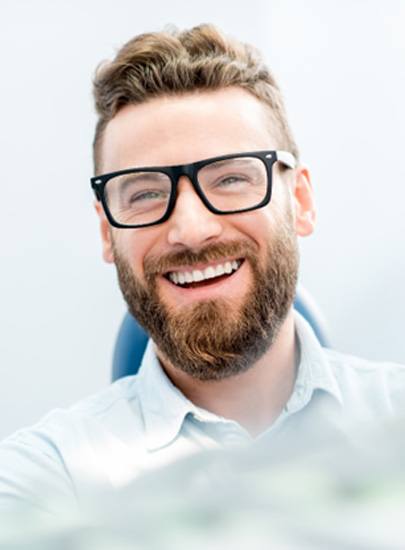 man smiling while sitting in dental chair 