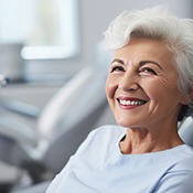 older woman smiling with her dentures in the dental chair