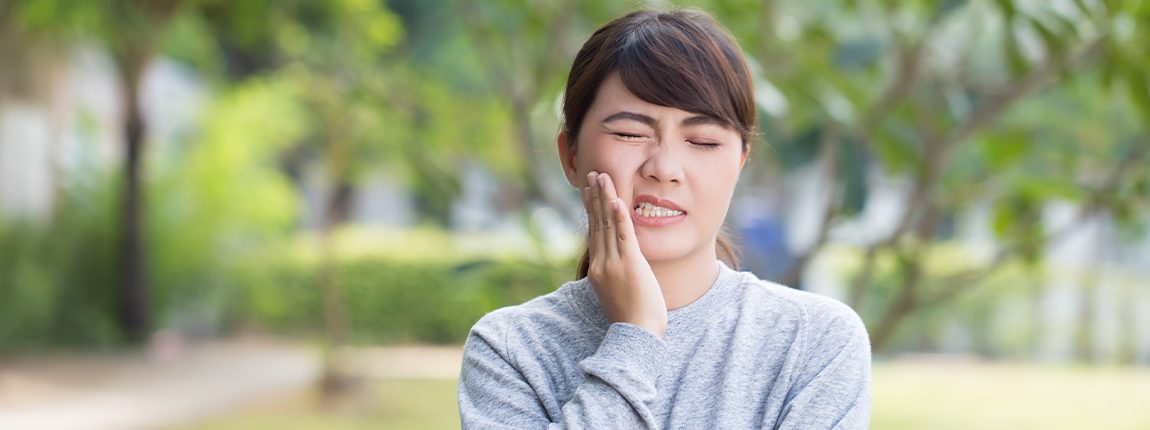 Woman in need of emergency dentistry holding cheek