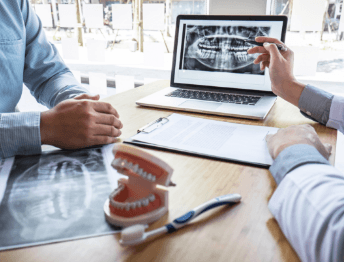 patient and dentist reviewing patient's smile on laptop