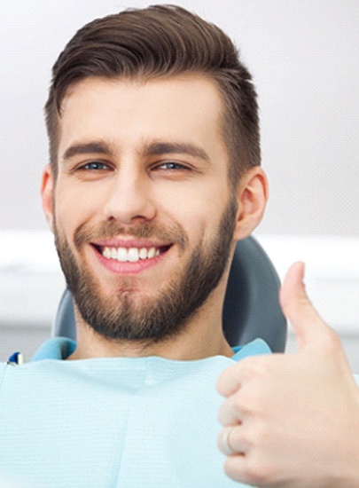 bearded man giving thumbs up in dental chair