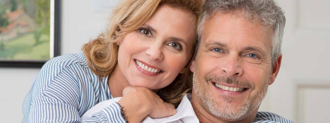 senior man and woman smiling and showing off their dental implants in Chula Vista 