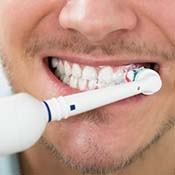 man brushing his teeth with an electric toothbrush 