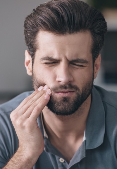 Man in mouth pain holding cheek