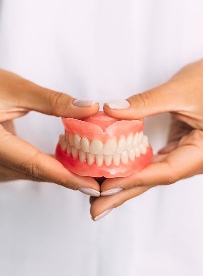 Hands holding full set of dentures