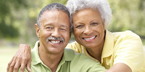 Man and woman with healthy smiles after replacing missing teeth