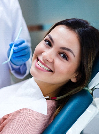 Woman smiling in dental chair after smile makeover in Chula Vista