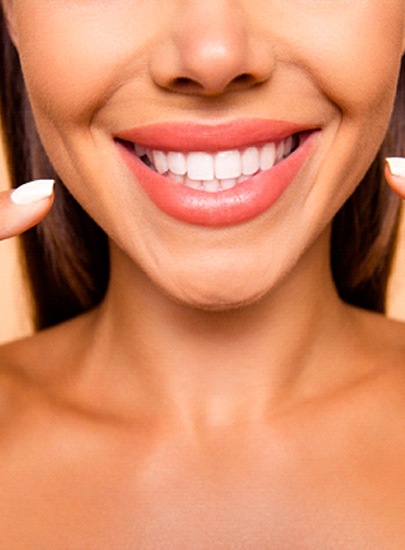 Woman pointing to her straight, white teeth
