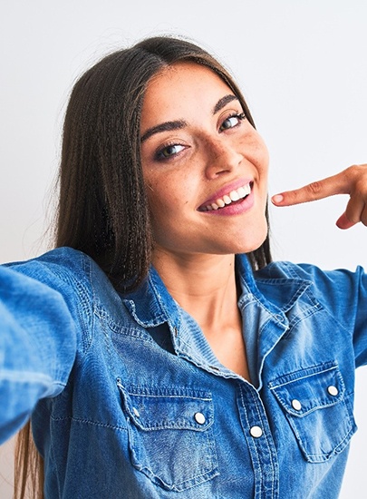 Woman smiling for picture while pointing to her white teeth