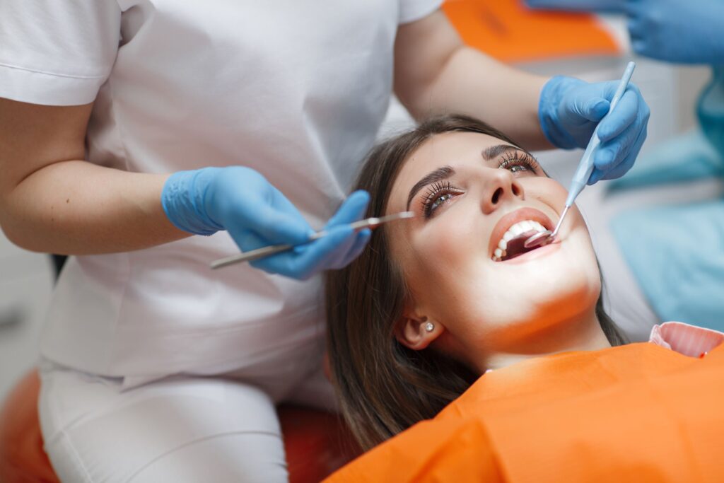 Woman in dental chair being treated by dentist in blue gloves
