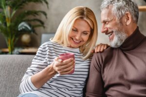 Couple in their 50s sitting next to one another on the couch.