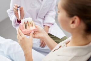 Dentist showing patient model of dental implants.