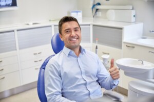 Man smiling and holding a thumbs up at his dentist