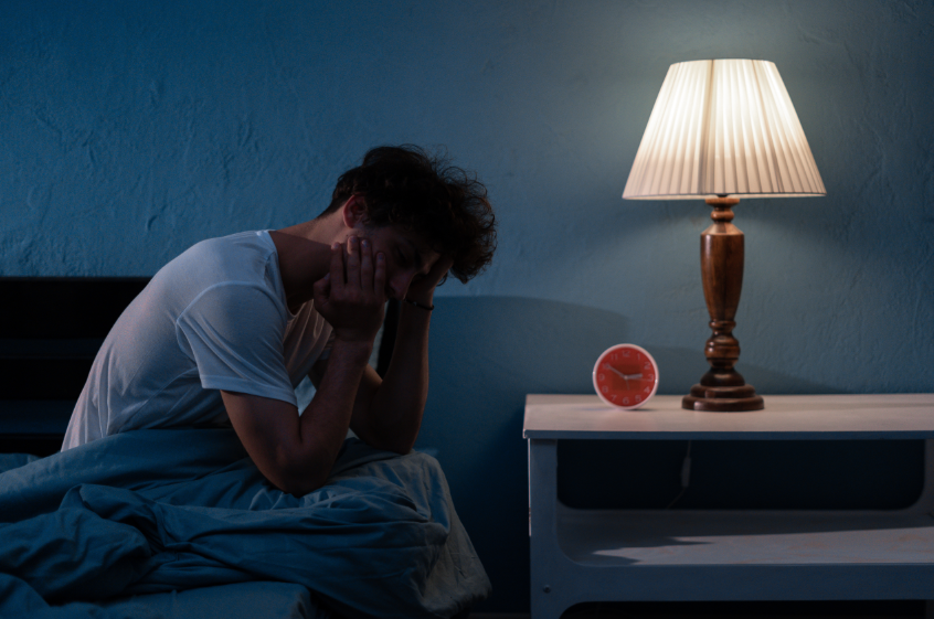 Man sitting up in bed at night, holding jaw